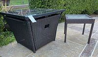 Fire table and side table set outdoors on patio showing overall condition and size comparison.
