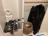 Photo of white dress shirt in packaging, assorted neck ties laid out, and two black jackets hanging