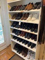 Wooden shelving unit displaying multiple pairs of men's shoes in various styles including loafers, slip-ons, dress shoes, boots and sneakers.