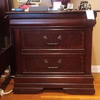 Front view of wooden nightstand showing two drawers with brass handles and detailed molding base.