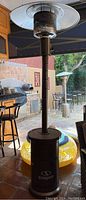 Full view of the propane outdoor heater showing base, tall pole, burner, and dome reflector in a patio setting.