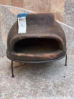 Front angled view of mini pizza stone oven on metal stand showing wide opening and rustic finish.
