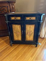 Front view showing two drawers with floral panels and two lower doors with matching floral design and keyhole escutcheon