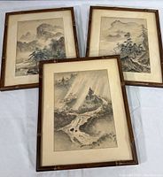Three framed Japanese landscape prints arranged on a surface, showing aged bamboo style frames and off-white mats.