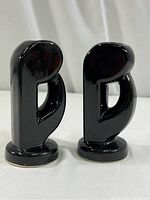 Pair of black gloss ceramic candle holders from side view showing shape and base.
