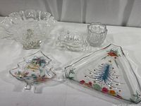 Full view of all 5 glass Christmas-themed tableware pieces arranged on white surface