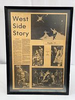 Full view of the framed newspaper article about West Side Story play with visible aging and black wood frame