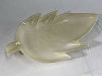 Top and side views of the soft gold colored alabaster leaf-shaped dish showing natural alabaster banding and carved footed base.
