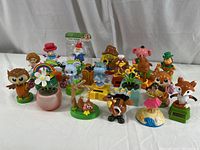Group photo of 21 colorful solar powered dancing figurines including animals and human characters orientated for display.