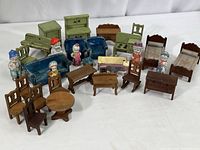 Wide view of the collection showing wooden doll house furniture pieces, blue upholstered sofas, and six ceramic figures.