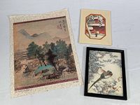 Photo showing the three prints: large unframed landscape print mounted on decorative fabric, small woodblock print, and framed pheasant print.