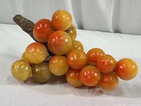 Full view of alabaster grape cluster with wood stem showing overall size and colors.