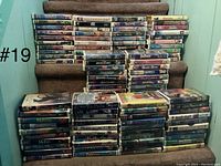 Photo shows stacked VHS tapes arranged on carpeted stairs with tape titles visible; tapes are mostly kids movies with colorful illustrated covers and some wear to cases.