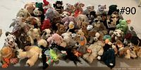 Wide view displaying approximately 40 assorted TY Beanie Babies plush toys in various animal forms, all with visible heart tags.