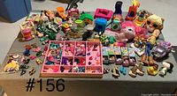 Wide view of assortment of Barbie shoes and various toys laid out on a table.