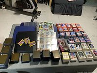 Photo of the entire collection spread on a table showing three binders filled with cards, several stacks of loose cards, and packs of plastic sleeves with team names.