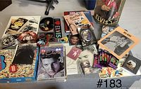 Photo of various Elvis Presley collectibles including magazines, cards, puzzle, and doll in box with wear