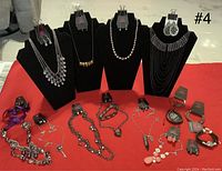 Full lot view showing necklaces on stands and earrings and bracelets laid out on red cloth