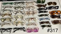 View showing the full collection of 29 eyeglasses and sunglasses including various styles, lens colors, and frame designs laid flat on a white surface.