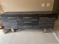 Front view of a long rectangular cabinet with five drawers and two side doors in gray wood grain finish on metal legs.