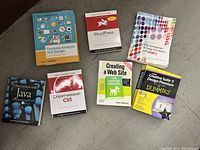 Photo showing seven different web development and related technology books arranged on a surface.