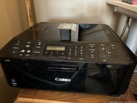 Black Canon MX410 all-in-one printer-scanner showing control panel with LCD and buttons for scan, copy, fax, and print functions