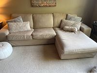 Full view of beige IKEA sectional couch with chaise in living room setting showing cushions and condition.