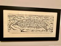 Framed black and white print showing detailed historical map of Seville in the 16th century, highlighting city layout and geographical features.
