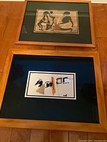 Photo of two framed African prints placed vertically on a floor, showing details of artwork and frames.