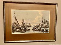 Framed picture showing historic London Docks with ships and boats on water under a cloudy sky, brown wooden frame and matte around the image.