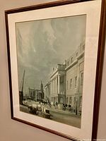 Framed print showing London Docks street scene with horses, carriages, and historic buildings under a cloudy sky.