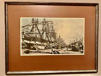 Framed print showing a historic scene of the London docks with multiple ships, dock workers and cargo.