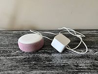Google Nest Mini light pink smart speaker with white charging cable and power adapter