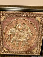 Close-up of the embroidered Thai figure riding an elephant within an ornate circular frame, showing detailed needlework and textile art.