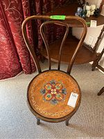 Front view of wooden chair showcasing curved backrest and hand painted round seat with floral pattern.