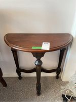 Front view of the wooden demilune table showing the table top, legs, and the supporting stretcher.