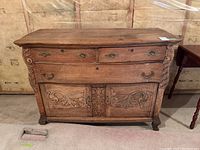 Front view of the wood dresser showing three drawers and carved double-door cupboard.