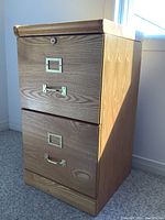 Front view of the two-drawer wooden filing cabinet showing locks, handles, and wood grain.