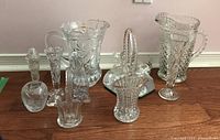 Group photo of multiple hand cut lead crystal items including jug, pitchers, vases, basket, and salt shaker showing detailed cut patterns and sizes.