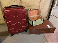 Photo showing all three pieces of luggage: red Jeep wheeled suitcase, brown vintage suitcase, and floral mini trunk with metal accents.