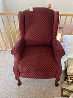 Front view of red wingback recliner showing fabric pattern and padded arms.