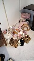 Photo showing sewing box, embroidery hoops, fabric pieces, spools of yarn and thread laid on carpeted floor.