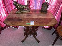 Front view of rustic wood table with decorative pedestal base and worn wood surface.