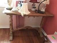 Front view of wood console table with decorative legs and items on top