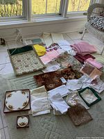 Photo of various table linens including napkins, doilies, table runners, and coasters arranged on the floor