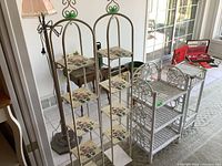 Full view of the lot showing two tall metal plant stands with floral tile shelves, white wicker shelf and wooden plant stand in background