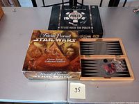 Display of the Wireless Plug and Play Poker game box, Star Wars Trivial Pursuit box, and open wooden travel game board with pieces visible.