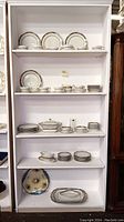 Full view of Limoges china dinnerware and tea ware arranged on shelves, showing plates, bowls, cups, serving dishes.