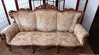 Full view of the Victorian sofa showing carved wood frame and floral upholstery.