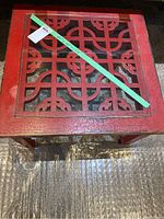 Top view of square red accent table showing glass inset and lattice design beneath glass.